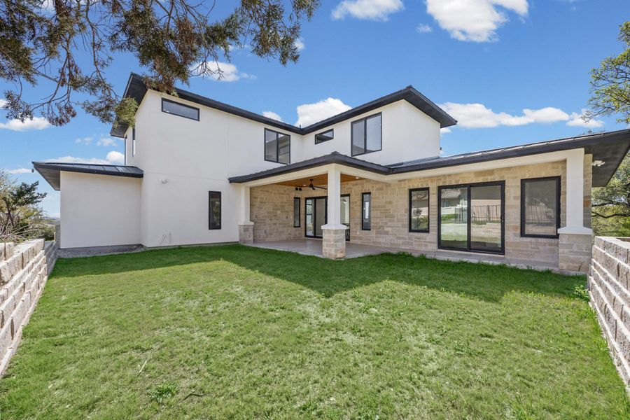 Back of property featuring a ceiling fan, a patio area, stucco siding, and stone siding