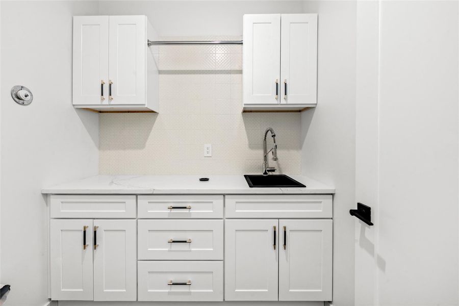 Bar area featuring white cabinetry, tasteful backsplash, and light stone counters