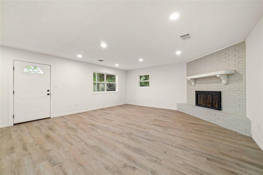 Unfurnished living room featuring visible vents, baseboards, light wood-type flooring, a fireplace, and recessed lighting Unfurnished living room featuring visible vents, baseboards, light wood-type flooring, a fireplace, and recessed lighting