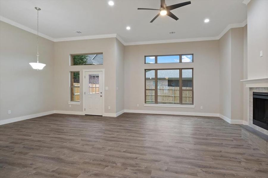 Unfurnished living room featuring a fireplace, hardwood / wood-style flooring, crown molding, and ceiling fan