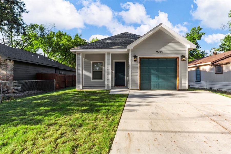 View of front facade featuring a front yard and a garage