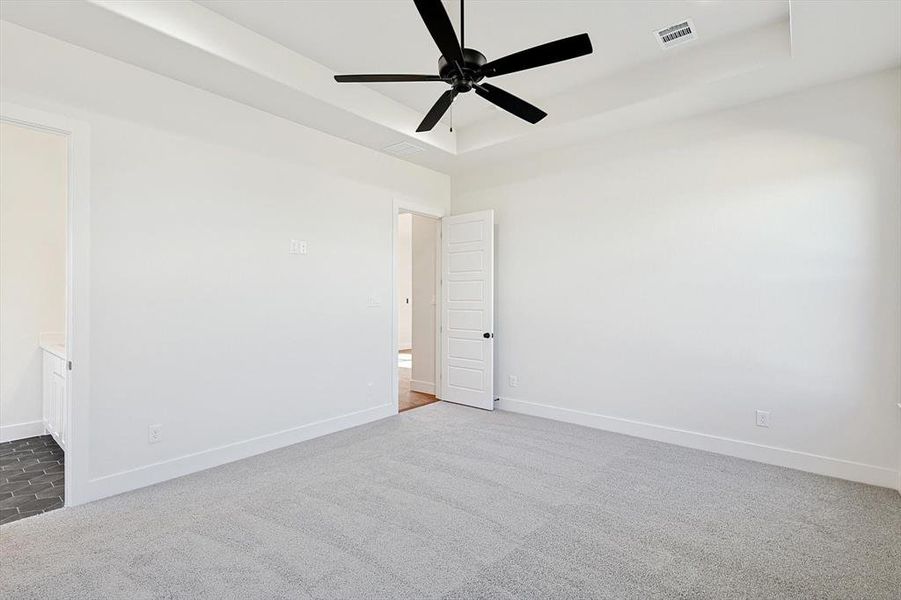 Primary Bedroom with boxed ceiling featuring carpet, ceiling fan