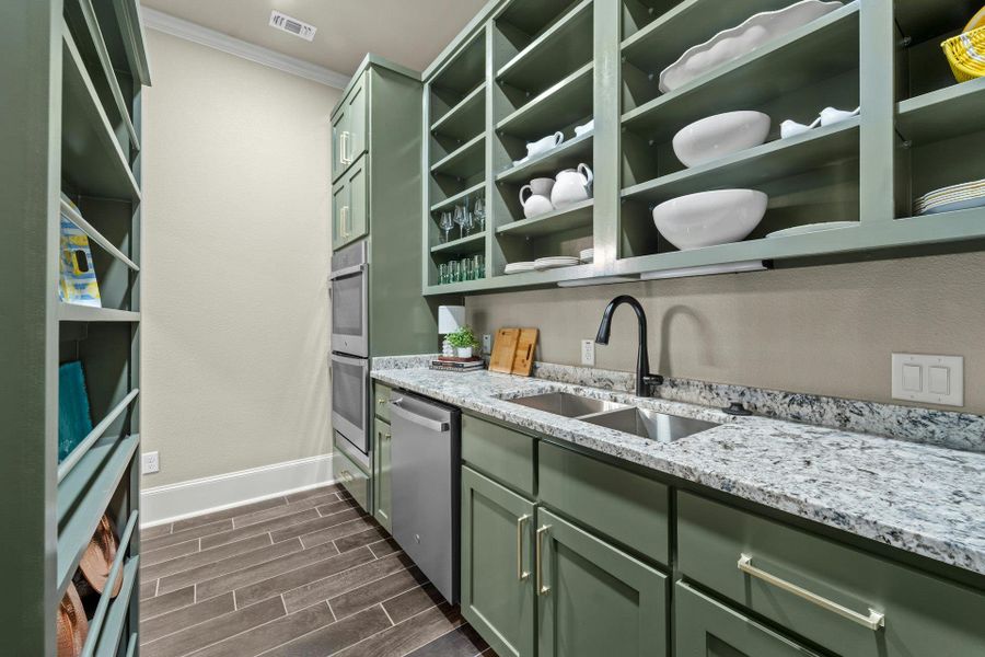Kitchen featuring a double stainless steel sink, black gooseneck faucet, light-toned granite countertop, green cabinetry, and stainless steel dishwasher