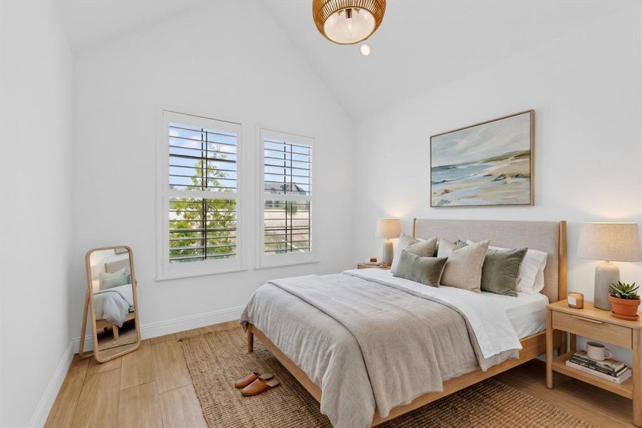 Vaulted ceiling bedroom featuring wood-finish flooring, plantation shutters, and a woven pendant light fixture Vaulted ceiling bedroom featuring wood-finish flooring, plantation shutters, and a woven pendant light fixture