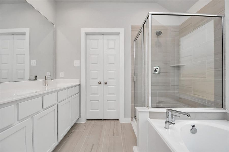 Delight in a spacious walk-in shower enveloped in stylish tile surround, unwind in a separate garden tub adorned with custom detailing. Sample photo of similar plan. As-built color and selections may vary.