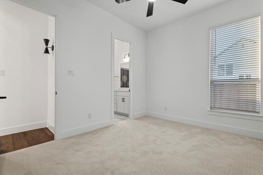 Unfurnished bedroom with carpet flooring, ceiling fan, and connected bathroom Unfurnished bedroom with carpet flooring, ceiling fan, and connected bathroom