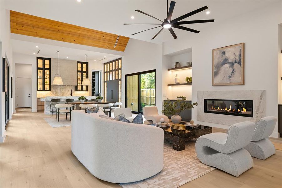 Spacious living area featuring light wood-finish flooring, a contemporary fireplace with a stone surround, and recessed lighting Spacious living area featuring light wood-finish flooring, a contemporary fireplace with a stone surround, and recessed lighting