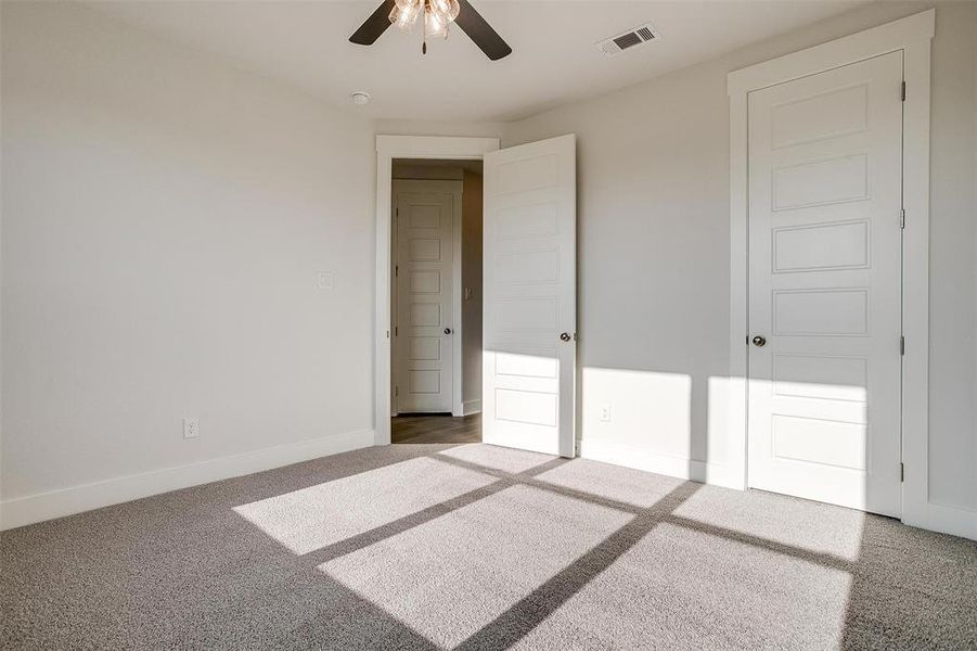 Unfurnished bedroom with ceiling fan and carpet flooring