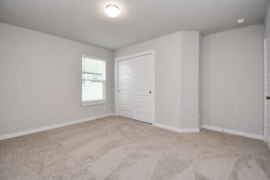 Secondary bedroom features plush carpeting, large windows that let in plenty of natural light, bright paint, and spacious closets. Sample photo of completed home with similar floor plan. Actual colors and selections may vary. Secondary bedroom features plush carpeting, large windows that let in plenty of natural light, bright paint, and spacious closets. Sample photo of completed home with similar floor plan. Actual colors and selections may vary.