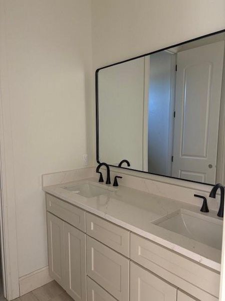 Full bath with double vanity and baseboards