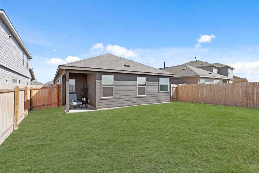 Back of house with a fenced backyard and a patio