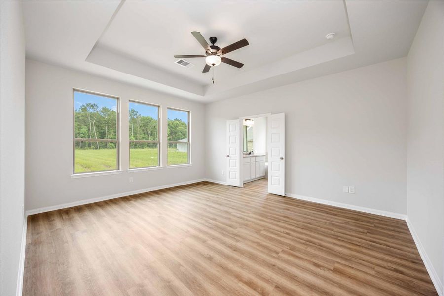 The primary bedroom features three large windows, vaulted ceiling with a ceiling fan and an ensuite bathroom. The primary bedroom features three large windows, vaulted ceiling with a ceiling fan and an ensuite bathroom.