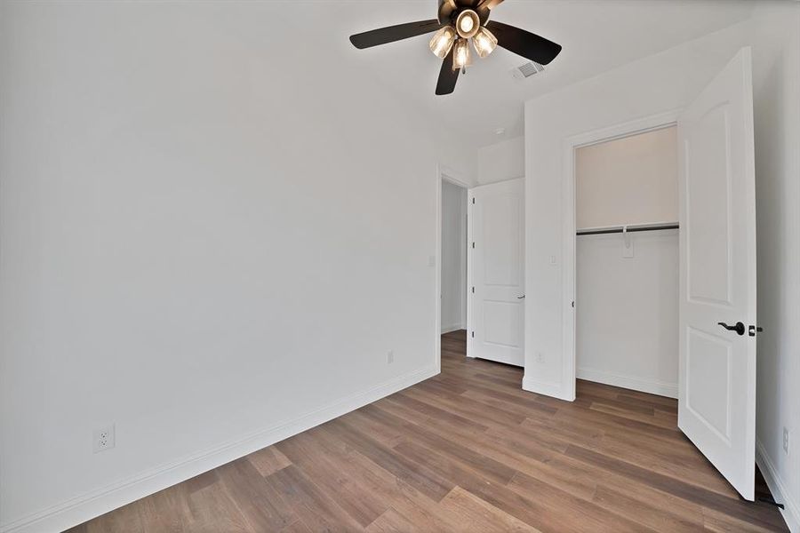 Secondary bedroom featuring wood finished floors, a closet, and a ceiling fan