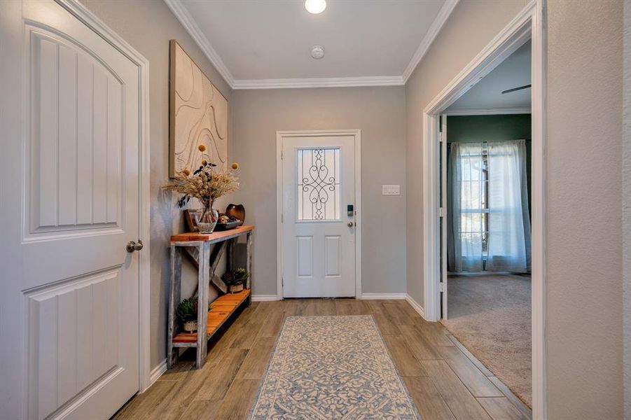 Foyer entrance featuring wood finish floors and crown molding