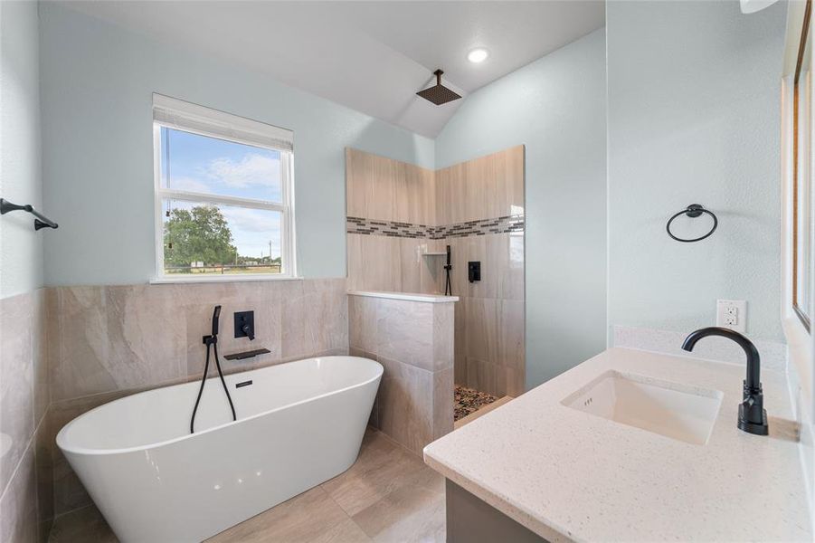 Bathroom with tile patterned flooring, tile walls, plus walk in shower, and vanity