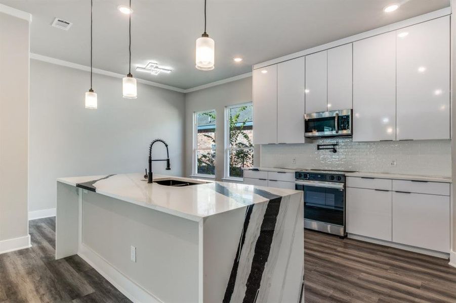 Kitchen featuring pendant lighting, white cabinetry, light stone countertops, appliances with stainless steel finishes, and tasteful backsplash