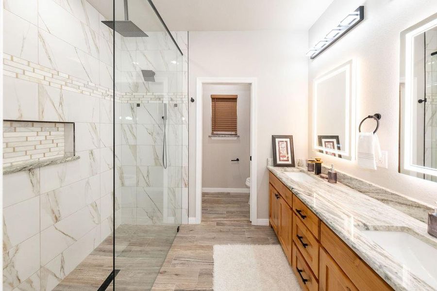 Bathroom with vanity, hardwood / wood-style floors, toilet, and tiled shower