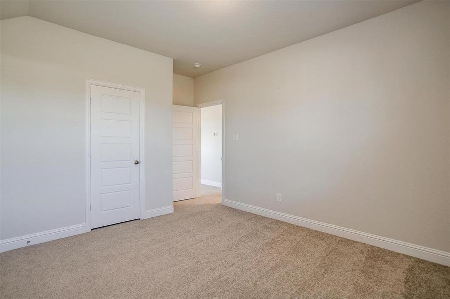 Unfurnished room featuring light carpet and lofted ceiling