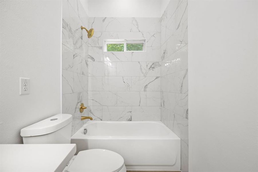 Full bathroom featuring tiled shower / bath combo, toilet, and vanity