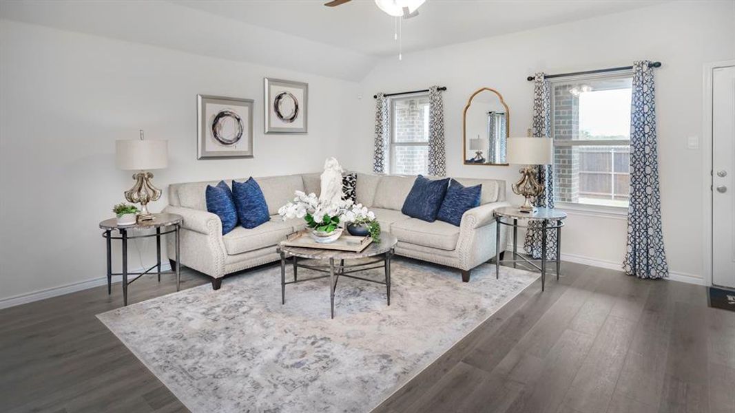 Spacious living area featuring wood-finish flooring, white walls, and multiple windows