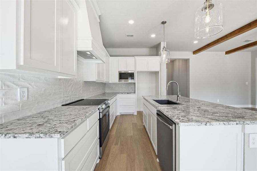 Kitchen with stainless steel appliances, decorative backsplash, recessed lighting, a kitchen island with sink, and white cabinetry Kitchen with stainless steel appliances, decorative backsplash, recessed lighting, a kitchen island with sink, and white cabinetry