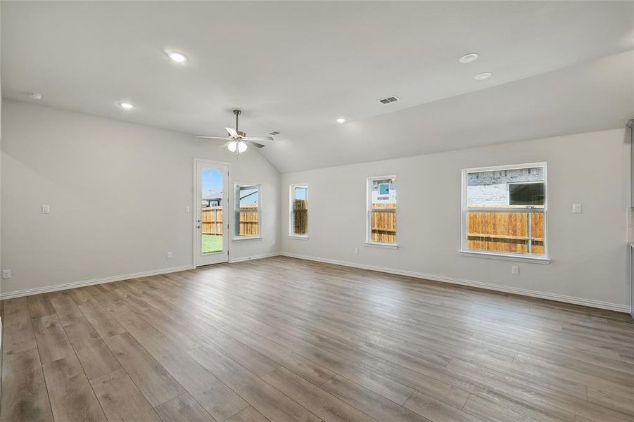 Spare room featuring a ceiling fan, plenty of natural light, lofted ceiling, wood finished floors, and baseboards Spare room featuring a ceiling fan, plenty of natural light, lofted ceiling, wood finished floors, and baseboards