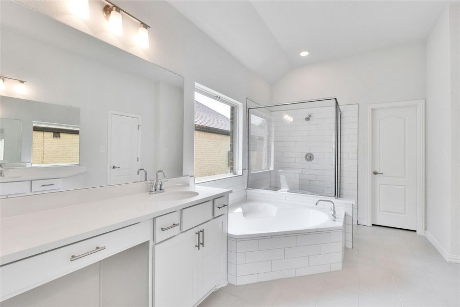 Full bathroom featuring a bath, tile patterned flooring, vaulted ceiling, a tile shower, and vanity Full bathroom featuring a bath, tile patterned flooring, vaulted ceiling, a tile shower, and vanity