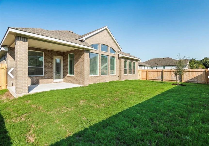 Rear view of house with a fenced backyard, brick siding, a patio, and roof with shingles