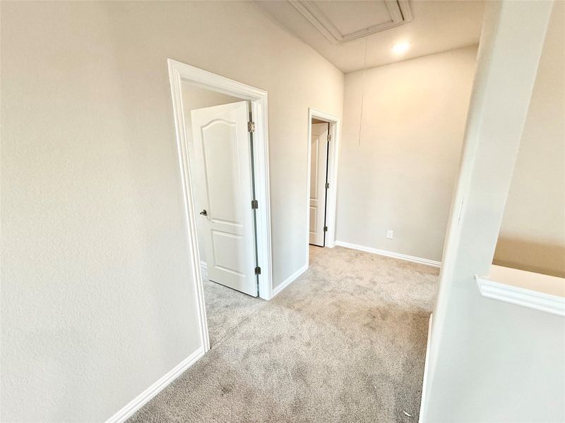 Corridor with attic access and light colored carpet Corridor with attic access and light colored carpet