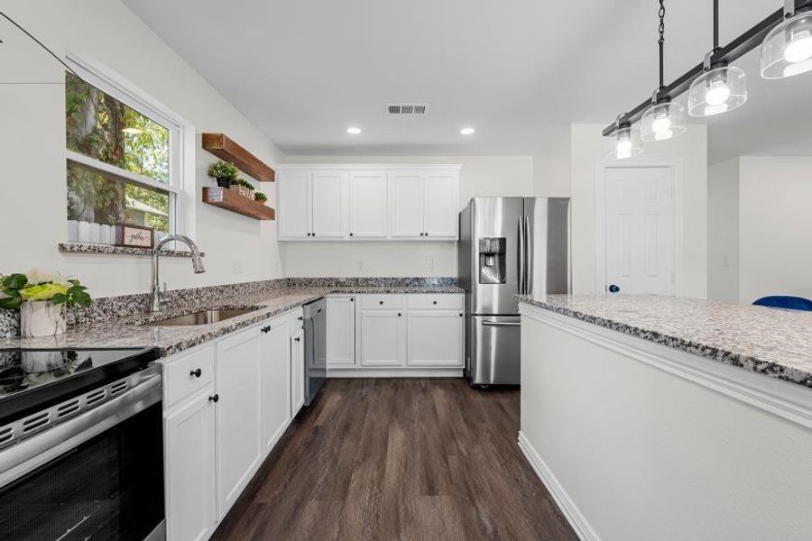 Kitchen with stainless steel appliances, light stone countertops, dark wood-type flooring, white cabinetry, and pendant lighting Kitchen with stainless steel appliances, light stone countertops, dark wood-type flooring, white cabinetry, and pendant lighting