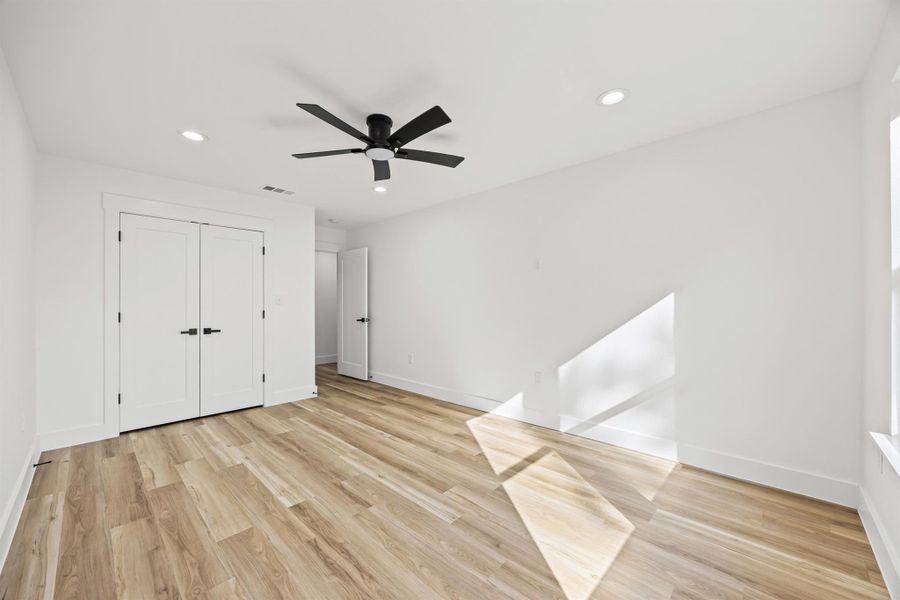 Same bedroom, different angel,  featuring light wood-type flooring, recessed lighting, ceiling fan, and a closet