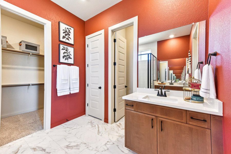 An inviting primary bathroom showcases a rich wooden vanity with ample storage and a spacious mirror. An inviting primary bathroom showcases a rich wooden vanity with ample storage and a spacious mirror.