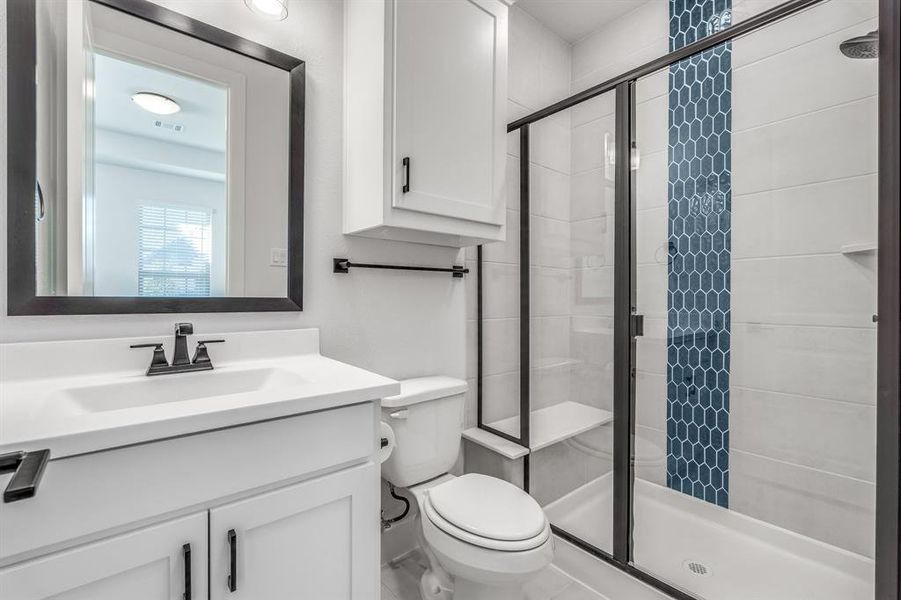 Bathroom with vanity, toilet, and a shower with shower door