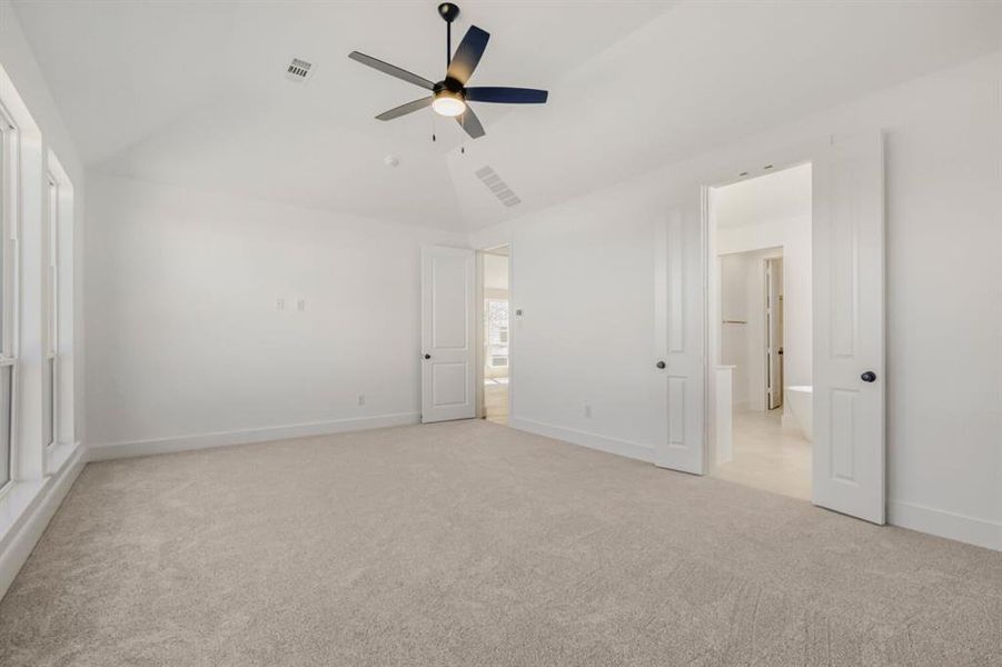 Unfurnished bedroom featuring light carpet, a ceiling fan, and vaulted ceiling
