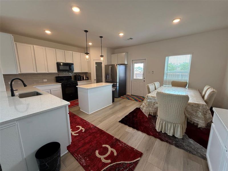 Kitchen featuring white cabinetry, light-toned countertops, tile backsplash, and wood-finish flooring