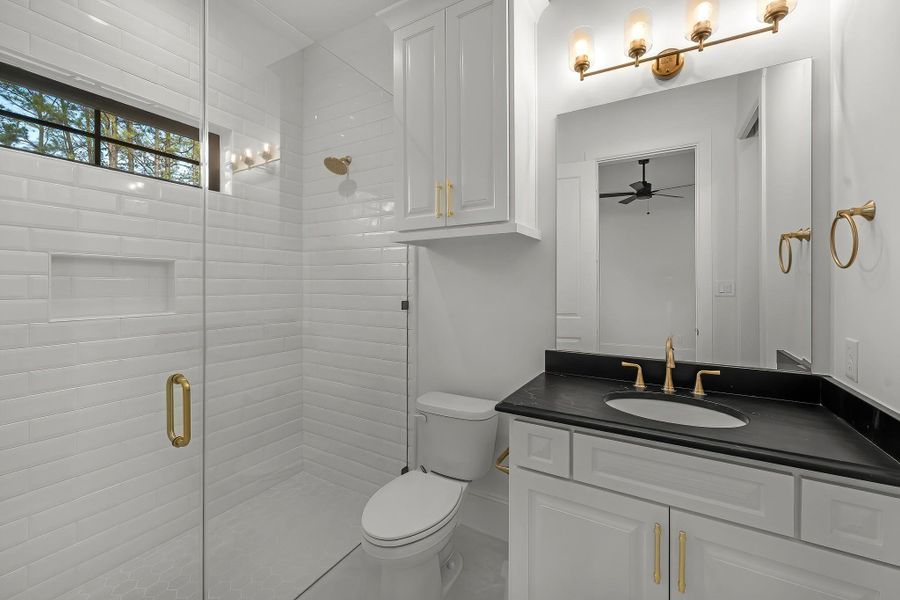 The secondary bath features tile flooring, white cabinetry and dark countertops and a walk-in shower. The secondary bath features tile flooring, white cabinetry and dark countertops and a walk-in shower.