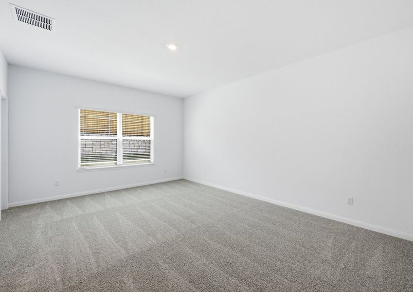 Spacious carpeted first-floor primary bedroom featuring a window with natural light. Spacious carpeted first-floor primary bedroom featuring a window with natural light.