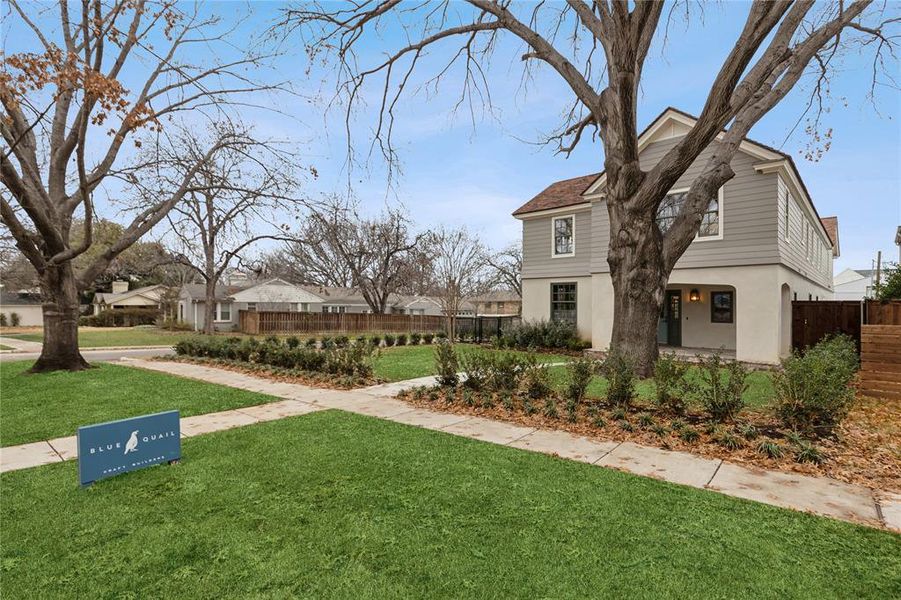 View of side of home featuring a residential view, stucco siding, fence, and a lawn