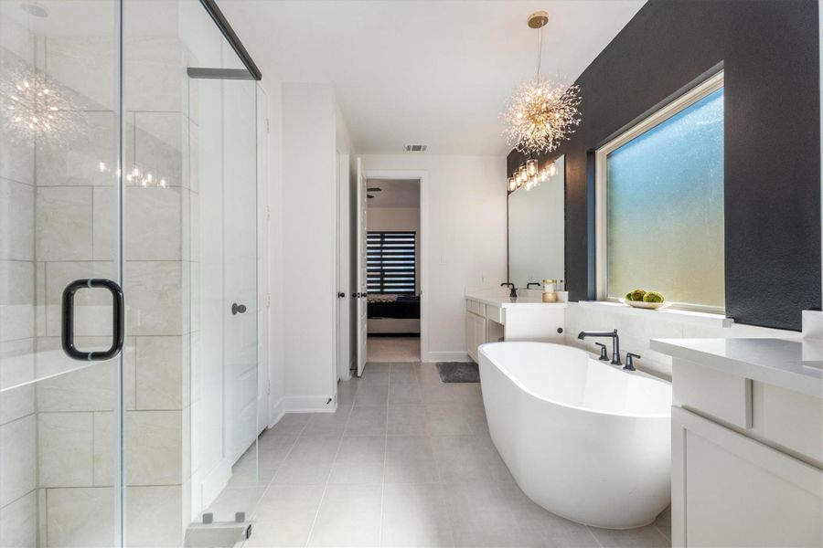 This modern bathroom features a spacious glass-enclosed shower, a sleek freestanding bathtub, and double sinks with contemporary fixtures. The large frosted window and elegant lighting add a touch of luxury.