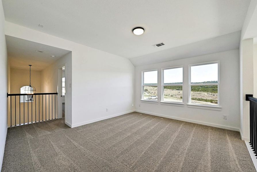 Carpeted spare room featuring lofted ceiling and a chandelier