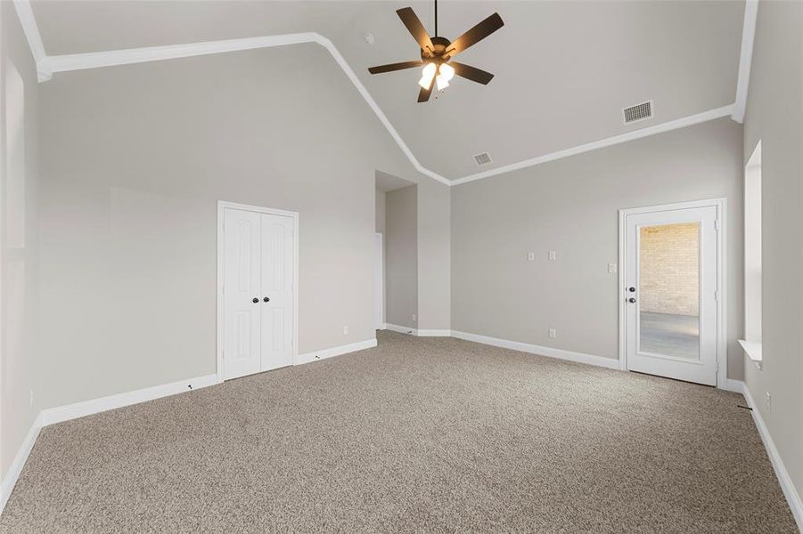 Empty room featuring ceiling fan, high vaulted ceiling, carpet floors, and crown molding