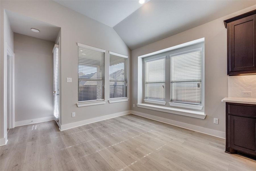 Unfurnished dining area with vaulted ceiling and light wood finished floors