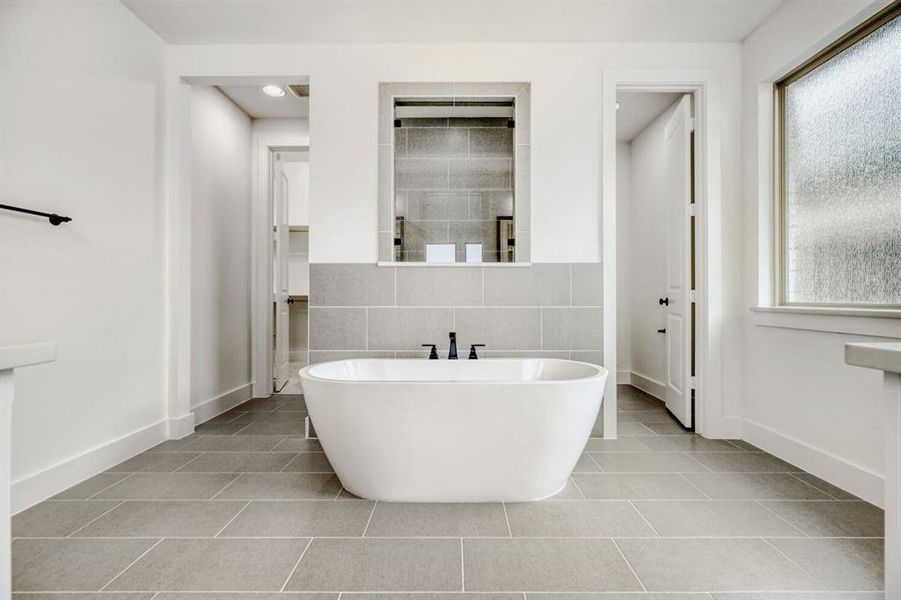 Full bath with tile walls, a freestanding tub, and light tile patterned flooring