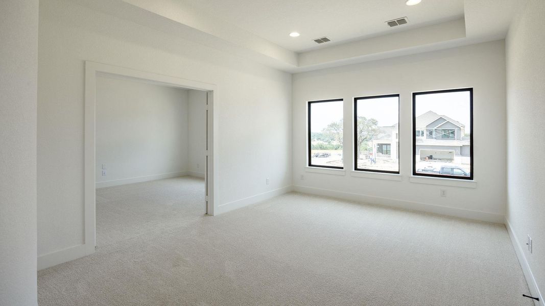 Empty room featuring light carpet, a raised ceiling, and recessed lighting