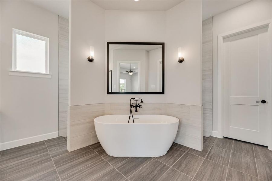 Full bath featuring a freestanding tub, tile walls, tile patterned floors, and a wainscoted wall
