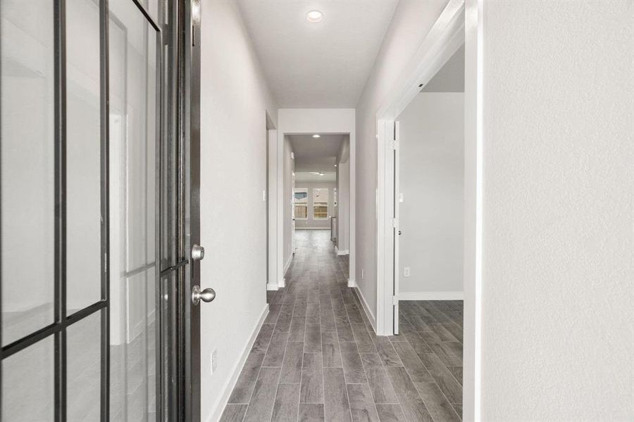 Greeted by a elegant glass front door, the entrance beckons with high ceilings, adorned with elegant wood-look tile flooring and oversized baseboards. Sample photo of completed home with same plan. Actual colors and selections may vary.