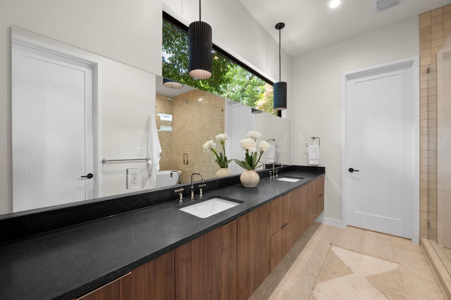 A chic bathroom with dual vanities, modern fixtures, and a serene window view. A chic bathroom with dual vanities, modern fixtures, and a serene window view.