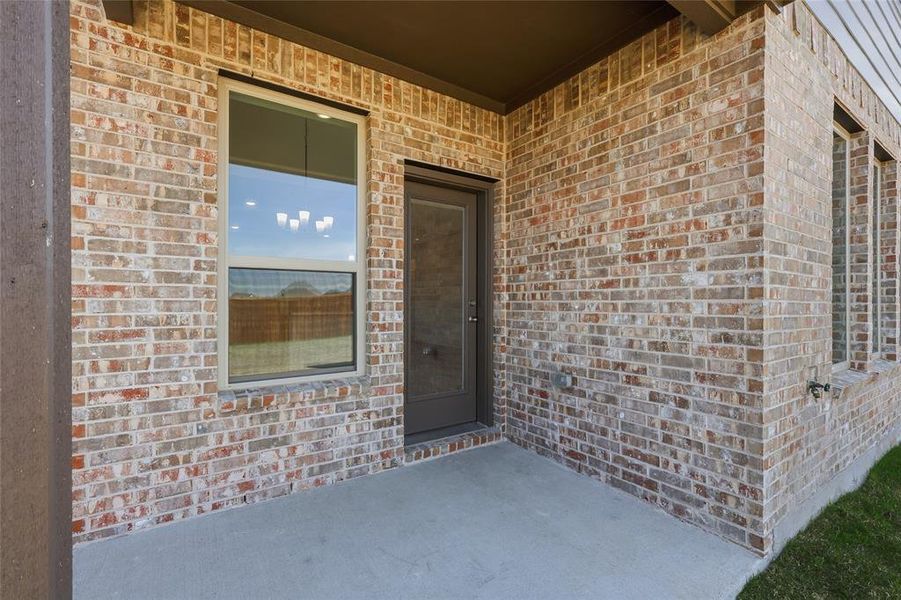 Covered patio featuring a solid concrete surface, exterior brick facade, and a single pane door