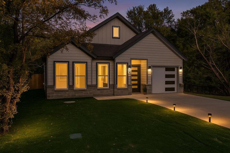 View of front of property featuring board and batten siding, concrete driveway, stone siding, and a garage