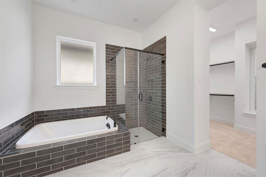 Full bathroom featuring a garden tub, a shower stall, a spacious closet, and light marble finish floors